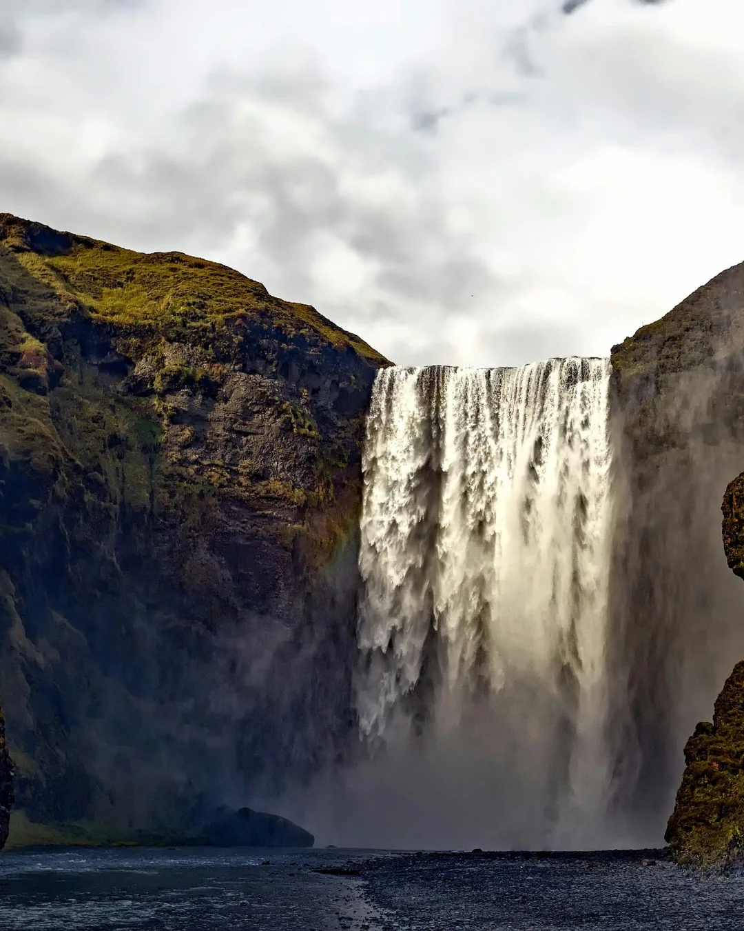 Cascada monumental entre acantilados verdes en Islandia